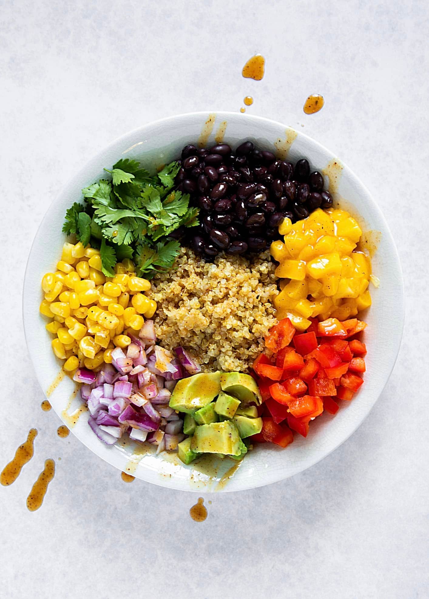 Salade colorée vivifiante avec quinoa, mais, herbes, haricot noir, poivron, avocat, oignon. jaune vert rouge mauve noir