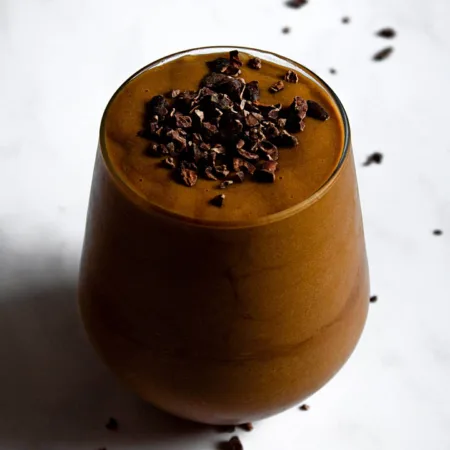 Verre rempli de smoothie frappé glacé au café avec éclat de cacao sur le dessus