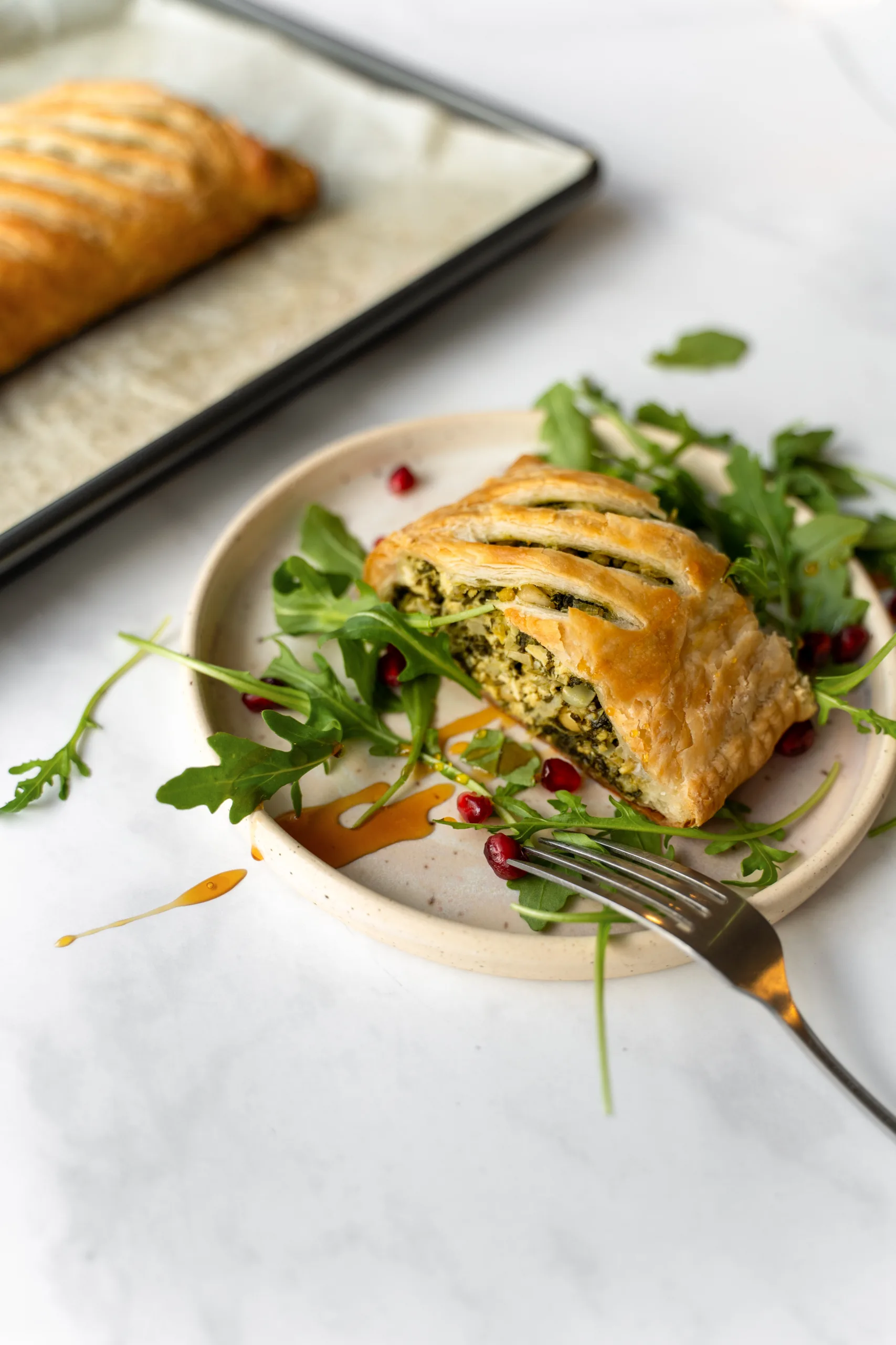 Portion de feuilleté aux épinards dans une assiette avec roquette et grenade