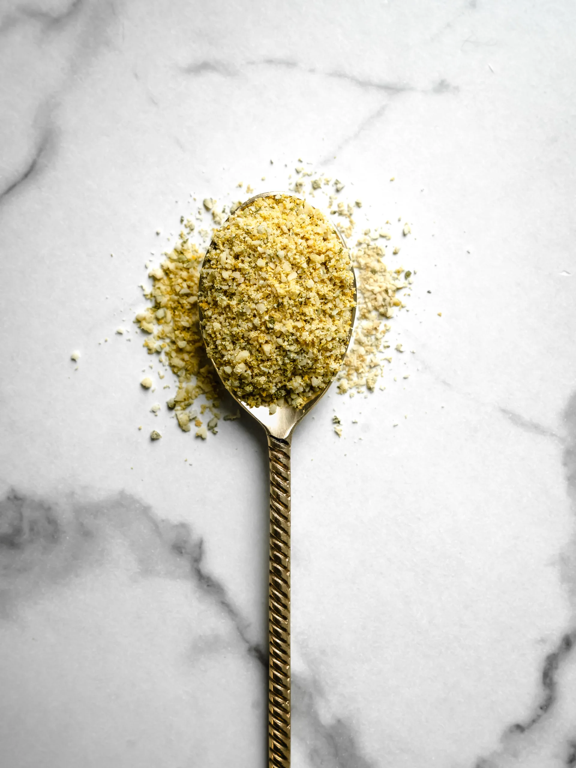 cuillère débordante de poudre de parmesan vegan jaune