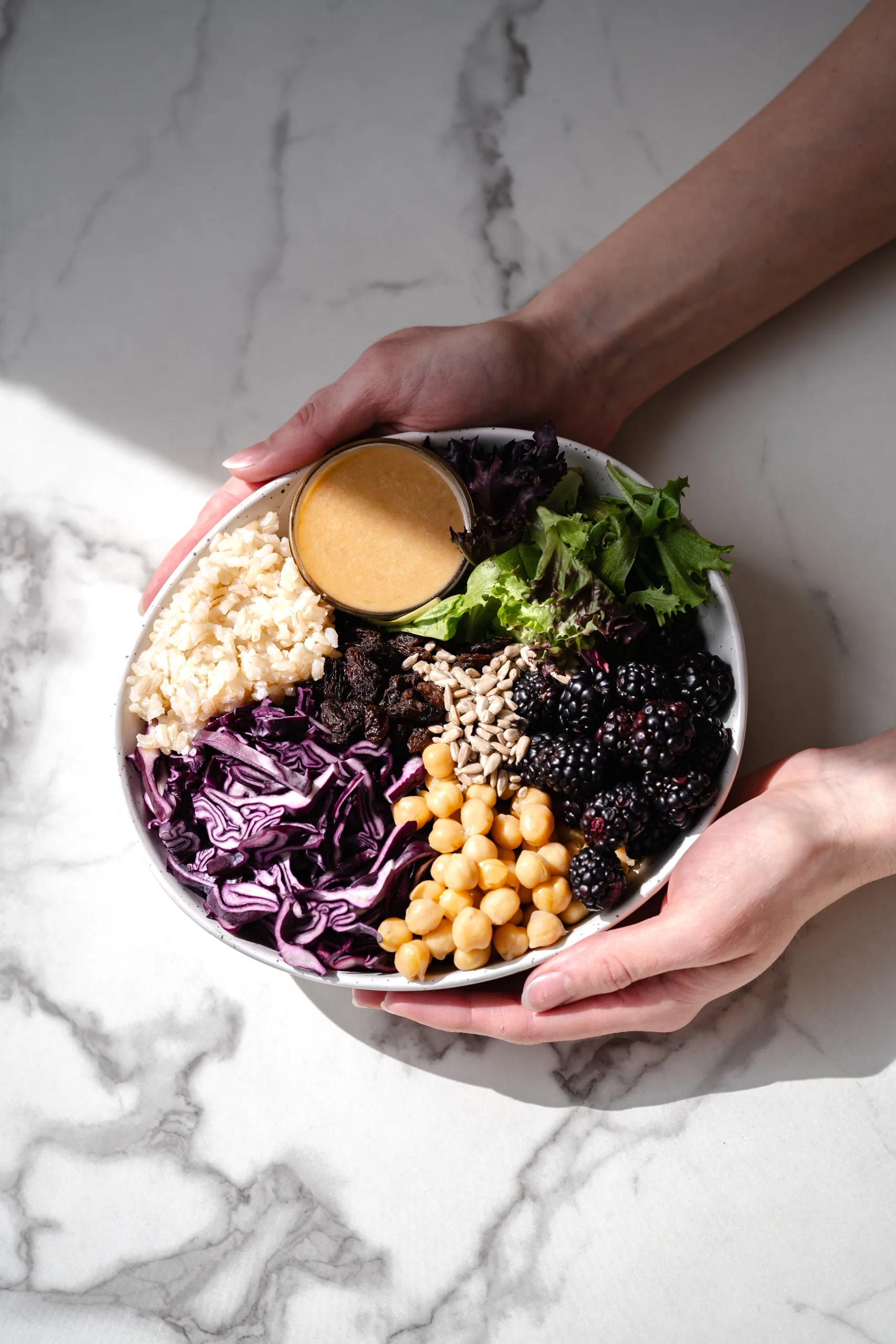 Mains qui tiennent un bol Bouddha avec des mûres et du tournesol