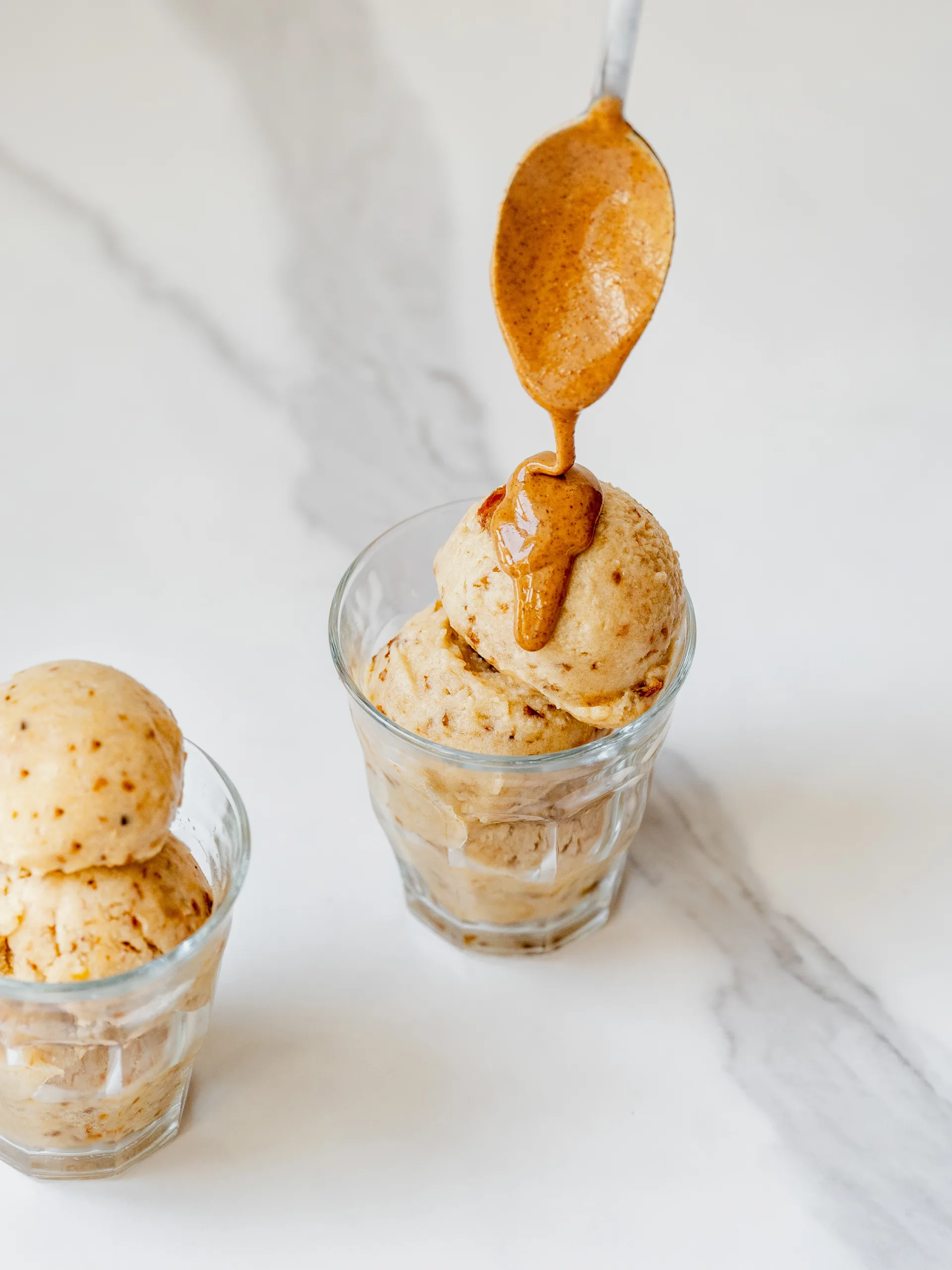 Cuillère versant du beurre d'amande sur la nice cream de banane au caramel salé